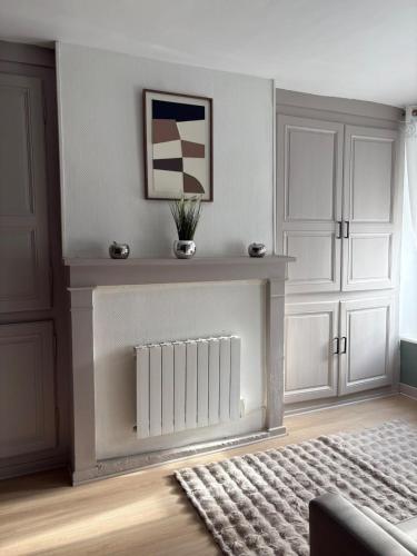 un soggiorno con un termosifone e mobili bianchi di Maison cosy & calme a Saint-Florentin