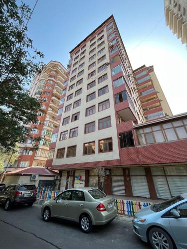 Twee auto's geparkeerd voor een hoog gebouw. bij House in Baku