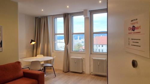 a living room with a couch and a table and windows at Campo Marzio 6 in Trieste