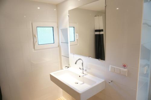 een witte badkamer met een wastafel en een spiegel bij Kustverhuur, Park Schoneveld, Zeester 27 in Breskens