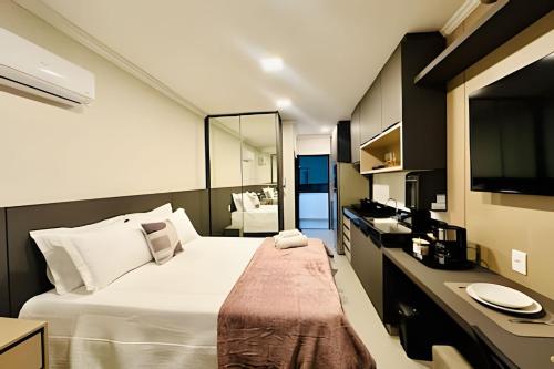 a bedroom with a large white bed and a television at Studio Pérola – Conforto, modernidade prox a UFU! in Uberlândia