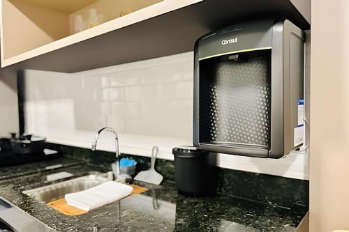 a kitchen with a sink and a tv on a counter at Studio Pérola – Conforto, modernidade prox a UFU! in Uberlândia