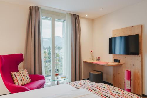 a hotel room with a bed and a chair and a window at Boutique Hotel Waldegg in Lucerne