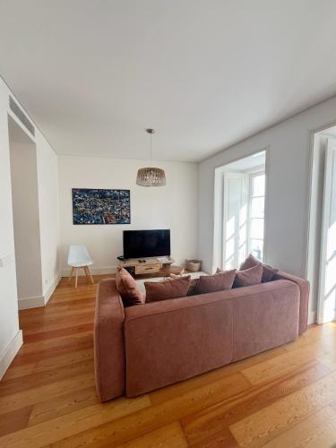 a living room with a couch and a tv at Sol ao Castelo - Downtown w Pool, Terrace, Parking in Lisbon