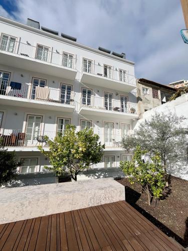 a white building with a wooden walkway in front of it at Sol ao Castelo - Downtown w Pool, Terrace, Parking in Lisbon
