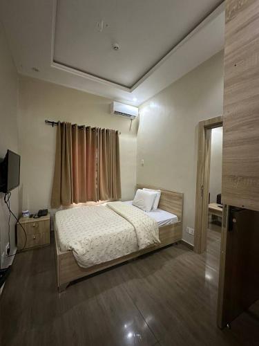 Un dormitorio con una cama y un televisor. en Maxwells Inn Yaba, en Lagos