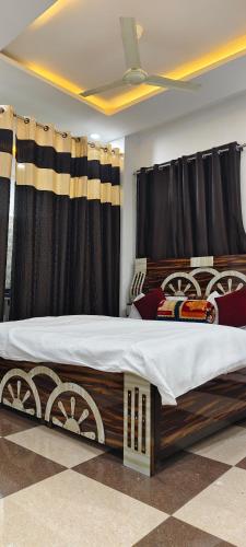 a bedroom with a large bed with black curtains at Dev Guest House in Aklera