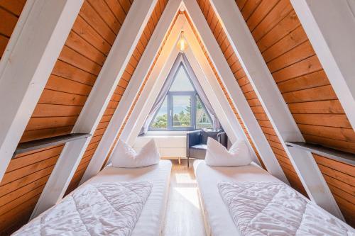 zwei Betten in einem Zimmer mit Fenster in der Unterkunft Ferienwohnpark Immenstaad am Bodensee Nurdachhaus Typ 7 ND 15 in Immenstaad am Bodensee