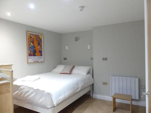 a white bedroom with a bed and a picture on the wall at Vibrant Studio Loft in the Heart of Soho in London