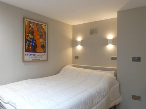 a bedroom with a white bed and a painting on the wall at Vibrant Studio Loft in the Heart of Soho in London