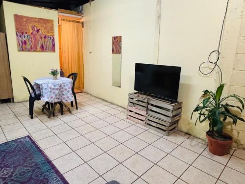 une pièce avec une table et une télévision et une table et des chaises dans l'établissement Arianas Place 2, à Huehuetenango
