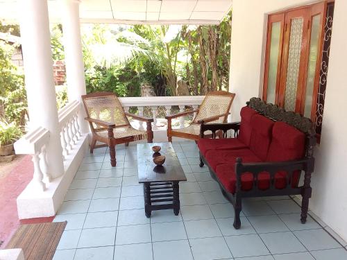 porche con sillas, sofá rojo y mesa en The Forest Villa, en Weligama