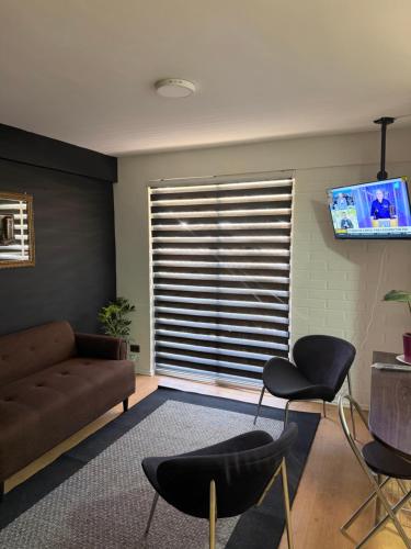 a living room with a couch and chairs and a television at Departamento cerca de la playa in La Serena