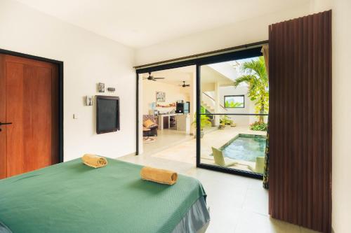 ein Schlafzimmer mit einem grünen Bett und einem Pool in der Unterkunft Senyum Villa in Canggu