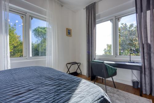 a bedroom with a bed and a desk and windows at Aparatman Residence in Rijeka