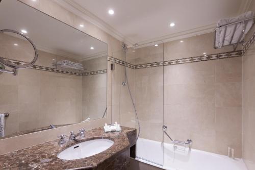 a bathroom with a shower, sink, and tub at Grand Hôtel de L'Univers Saint-Germain in Paris