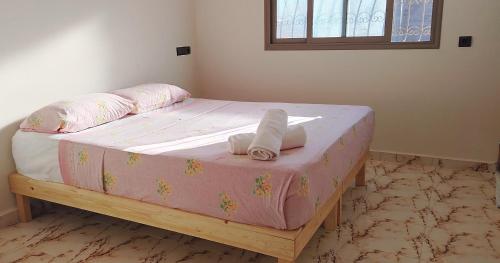 a bedroom with a pink bed with towels on it at Dar Fatima in Aït Ali