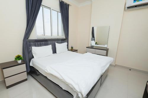 a bedroom with a large white bed and a mirror at صلالة الوسطى - نسائم صلاله للأجنحة والشقق الفاخرة Nassayem Salalah Hotel Apartments & Suites Salalah Center in Salalah