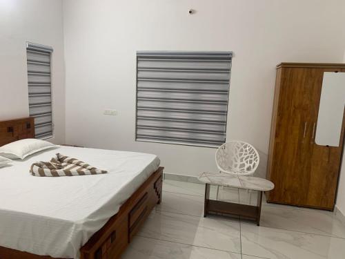 a white bedroom with a bed and a chair at The white luxury Homestay in Thekkady