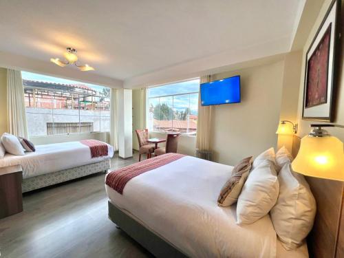 a hotel room with two beds and a large window at Hotel Chinchero Boutique & Tours in Chinchero