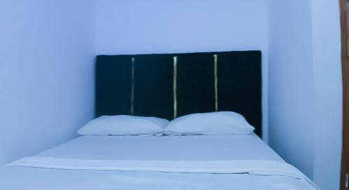a bed with a black head board with two pillows at Família Augusto in Luanda