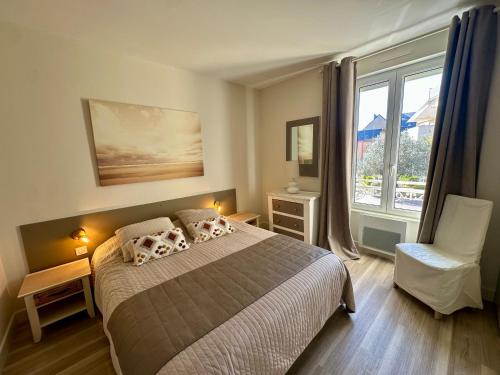 a bedroom with a bed and a chair and a window at Résidence du Parad'Ice in Dinard