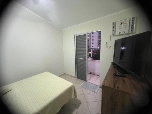 a room with a tv and a bed and a window at Condomínio Martim de Sá in Caraguatatuba