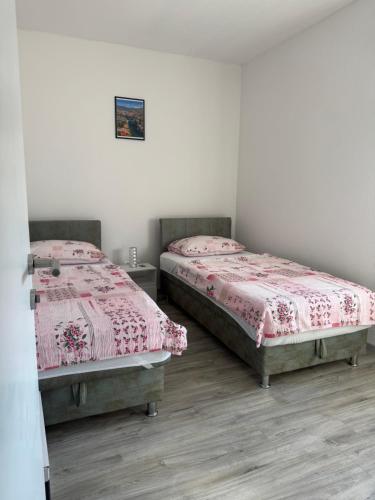 two twin beds in a room with white walls at Hubby Resort in Mostar