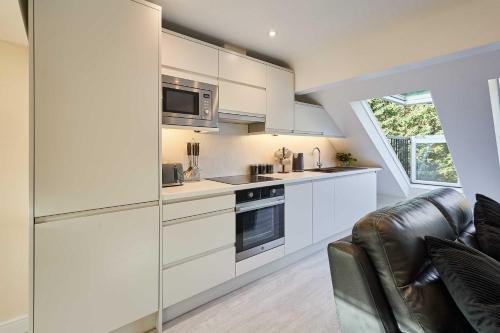 a kitchen with white cabinets and a microwave at Host & Stay - Ross's View in Whitby