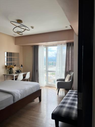 a bedroom with a bed and a desk and a window at Abreeza Tower 1 in Davao City