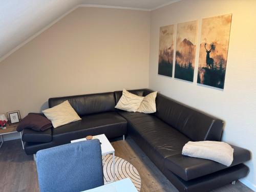 een woonkamer met een zwarte leren bank bij Eifelnest Stadtkyll in Stadtkyll