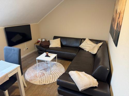een woonkamer met een zwarte leren bank en een tafel bij Eifelnest Stadtkyll in Stadtkyll