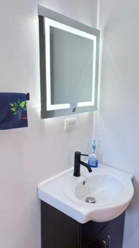 a bathroom with a white sink and a mirror at Casa Colibrí Playa Blanca in Paquera
