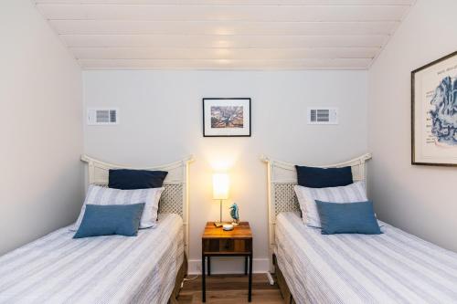 2 Betten in einem kleinen Zimmer mit einem Nachttisch in der Unterkunft Ocean Shade in Edisto Beach