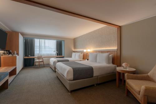 Sonesta Hotel Miraflores في ليما: غرفة فندقية بسريرين وكرسي