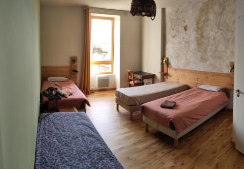 a room with three beds and a window at A la belle étoile - Auberge in Mellionnec