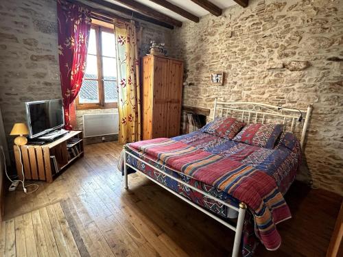 una camera da letto con un letto e una TV in una stanza di Maison de campagne a Nanteuil-en-Vallée