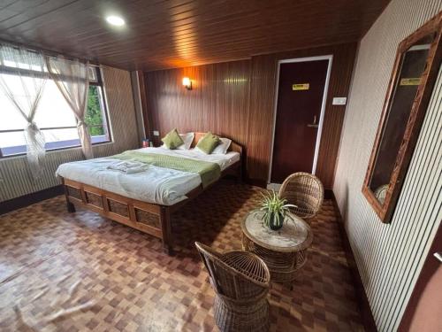 een slaapkamer met een bed, een tafel en stoelen bij P Square Resto Cafe n Stay in Darjeeling