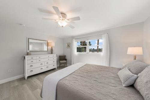 een witte slaapkamer met een bed en een plafondventilator bij Tranquil Tides in Sanibel Island