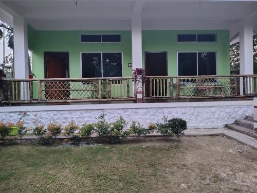 Casa verde con balcón y algunas plantas en Deer Dee Home Stay, en Jyoti Gaon