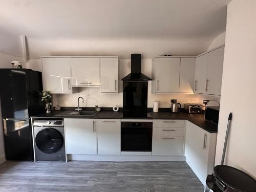 a kitchen with white cabinets and a black refrigerator at 1 bed flat, free parking, 10 mins BHX airport, free WiFi in Widney Manor Station