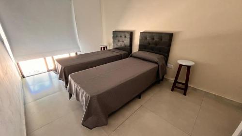 ein Schlafzimmer mit zwei Betten und einem Hocker darin in der Unterkunft Piccolo Posto in Neuquén