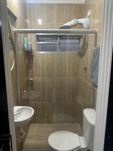 a bathroom with a shower and a toilet and a sink at Apartamento canto do forte in Praia Grande
