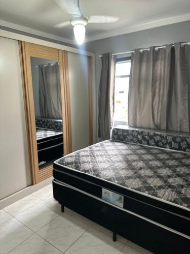 a bedroom with a bed in a room with a mirror at Apartamento canto do forte in Praia Grande