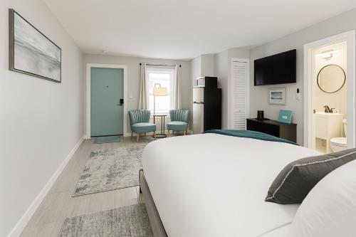 a white bedroom with a bed and a table and chairs at 1915 Beach Club in Daytona Beach