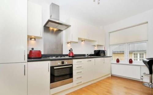 a kitchen with white cabinets and a stove top oven at Oxford City Apartment in Jericho Spacious Modern Free Parking, Walk to Bus, Rail and University in Oxford