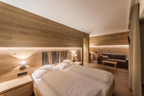 - une chambre avec un grand lit et un canapé dans l'établissement Hotel Garni Dolomieu, à Selva di Val Gardena