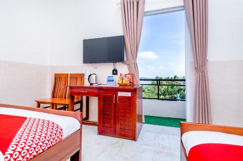 a hotel room with a television and a bed and a desk at Magnolia Hotel Cam Ranh in Cam Ranh