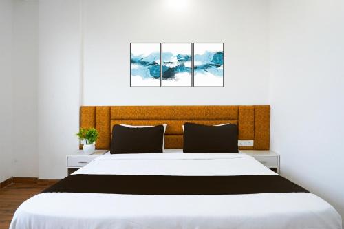 a bedroom with a large bed with three paintings on the wall at Hotel O Noida Sky Suites Sector 44 Near botanical metro in Badarpur