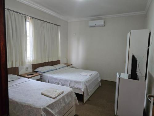 a hotel room with two beds and a flat screen tv at Hotel Pousada Accordes in Campo Grande
